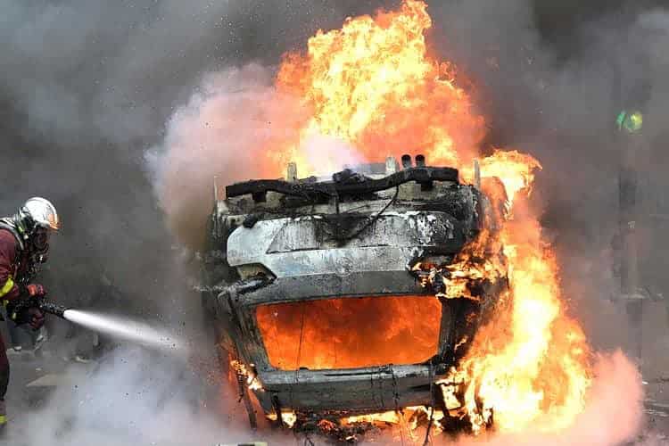 Un pompier éteint une voiture en feu à la fin d'une commémoration.