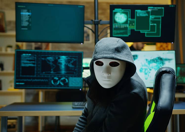 Masked hacker wearing a hoodie to hide his identity. Internet criminal.