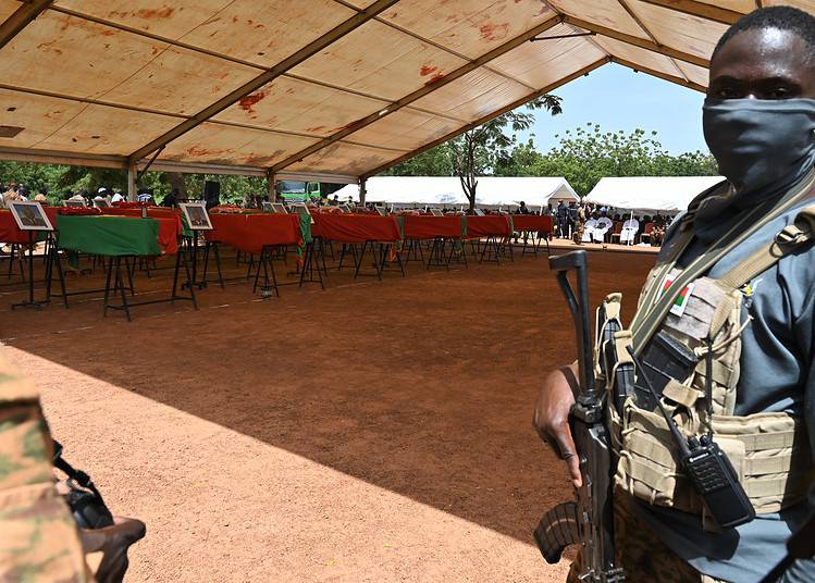 Un soldat monte la garde pendant les funérailles de 27 soldats tués alors qu'ils escortaient 207 véhicules dans un convoi à Gaskinde, lors d'une cérémonie au camp militaire Général Sangoule Lamizana à Ouagadougou le 8 octobre 2022.