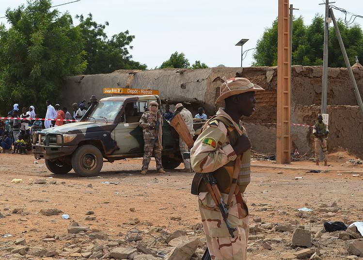 Des soldats maliens se tiennent à côté d'un bâtiment détruit le 13 novembre 2018 à Gao, après un attentat suicide à la voiture piégée qui a tué trois personnes. / AFP/