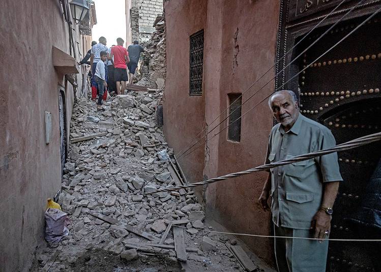 Un homme regarde des habitants naviguer dans les décombres de la vieille ville de Marrakech, endommagée par le tremblement de terre, le 9 septembre 2023. (Photo par FADEL SENNA / AFP)